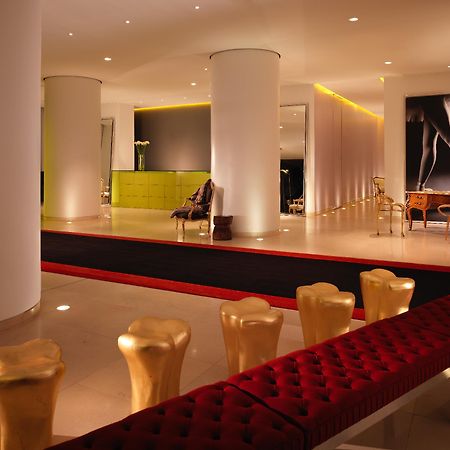 Hotel St Martins Lane Londra Esterno foto The photo shows a modern and stylish interior space, possibly a lobby or a lounge area. It features sleek white pillars and a polished floor, illuminated by soft ambient lighting. On one side, there is a green seating area, while on the opposite side
