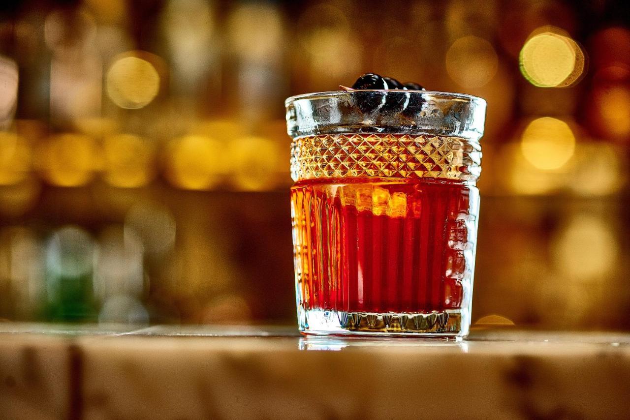 Hotel St Martins Lane Londra Esterno foto The photo shows a stylish glass filled with a dark red cocktail. The glass has a textured design and is topped with a couple of dark garnishes, possibly cherries. The background is softly blurred, highlighting the drink and suggesting a warm, invitin