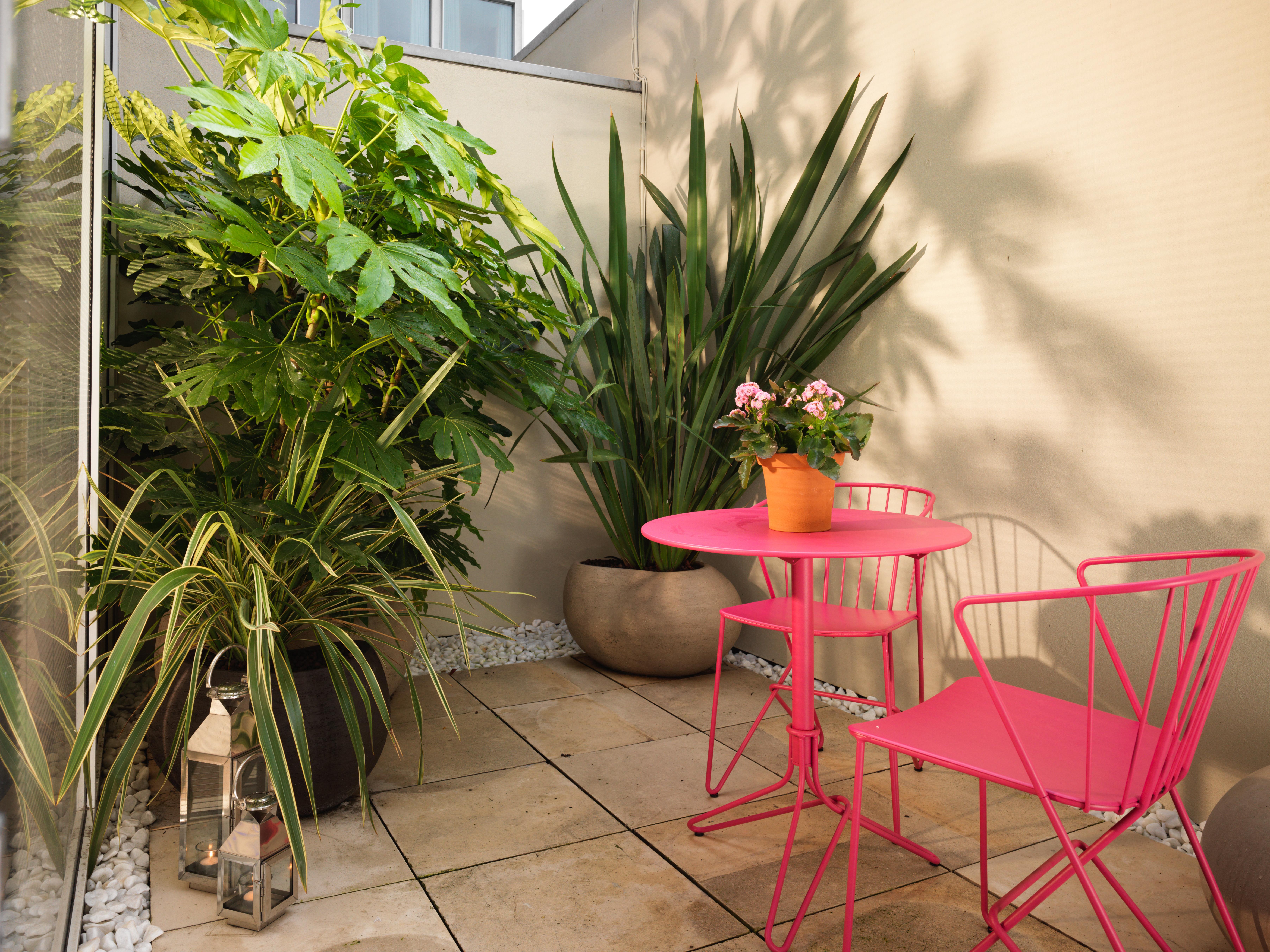 Hotel St Martins Lane Londra Esterno foto The photo shows a small outdoor area or balcony with a cozy setup. In the center, there is a round pink table with two matching pink chairs. On the table, there is a potted plant with pink flowers. Surrounding the table are various plants, including 