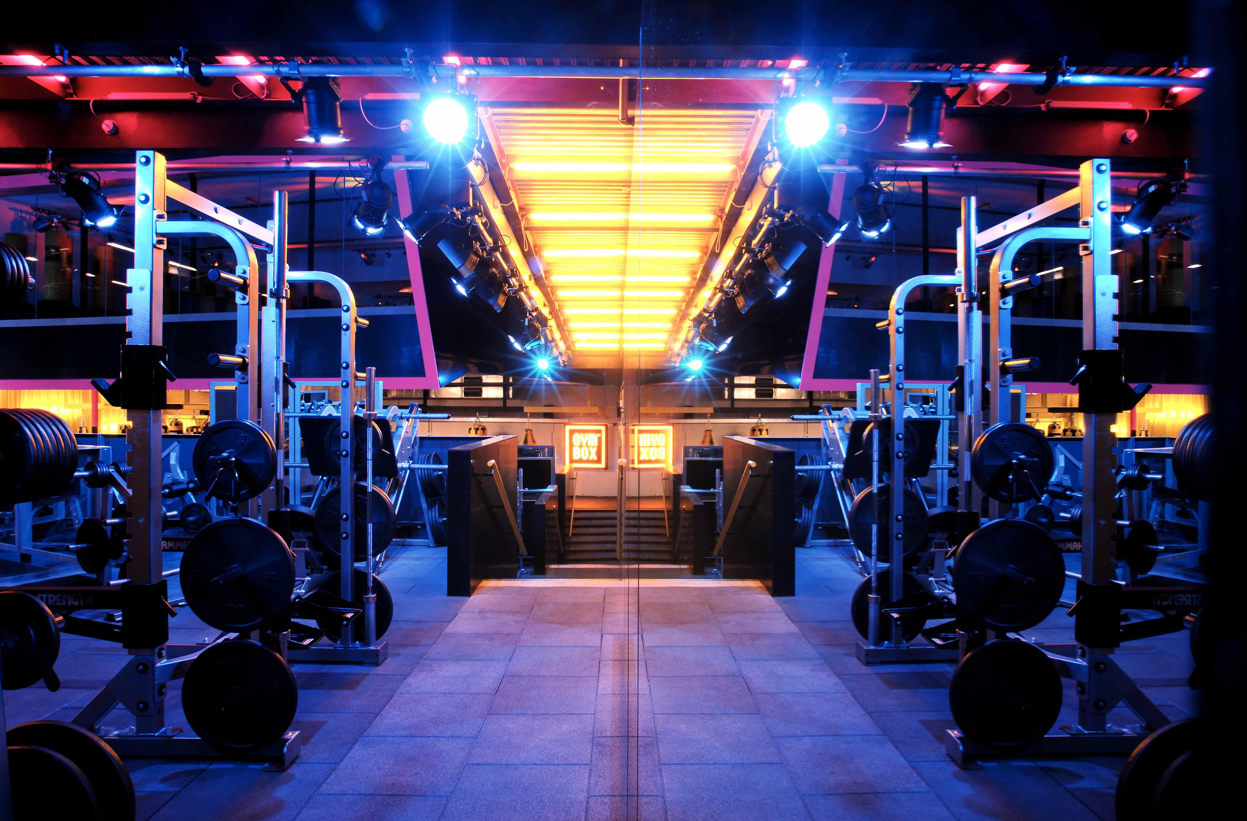 Hotel St Martins Lane Londra Esterno foto The photo depicts a modern gym interior, characterized by a brightly lit space with blue and orange lighting. In the foreground, there are multiple gym equipment setups, including weightlifting machines and benches. The gym features a sleek and conte