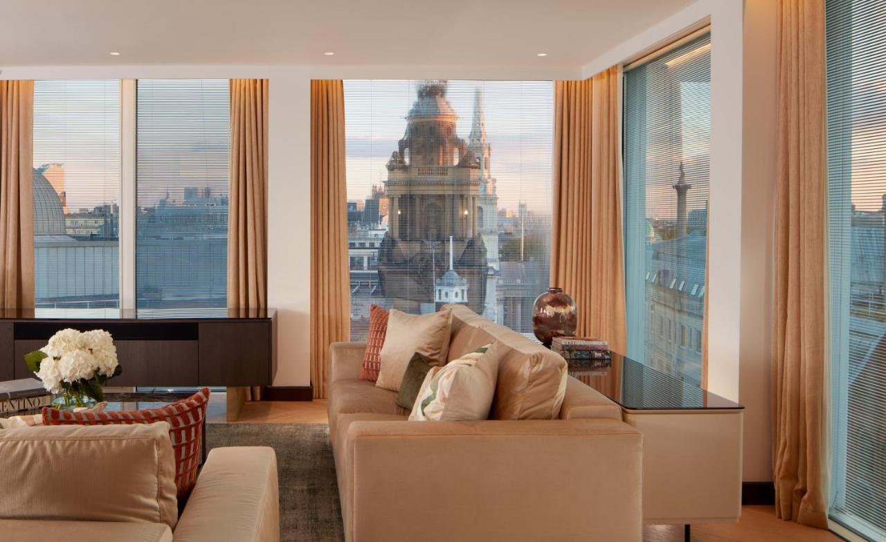Hotel St Martins Lane Londra Esterno foto The photo depicts a stylish and modern living room space. The room features large windows with sheer curtains, allowing natural light to fill the area. A plush beige sofa with decorative cushions is positioned centrally, creating a cozy atmosphere. I