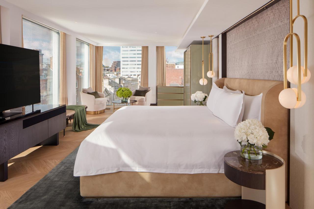 Hotel St Martins Lane Londra Esterno foto The photo shows a modern hotel room featuring a large, comfortable bed with white bedding. The room has large windows that provide natural light and a view of the cityscape outside. There is a stylish flat-screen TV mounted on the wall and a dark woo