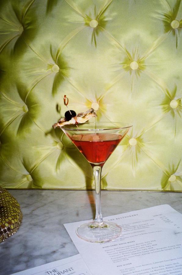 Hotel St Martins Lane Londra Esterno foto The photo depicts a cocktail served in a classic martini glass. The drink appears to be a reddish color, likely indicating it contains ingredients like cranberry or grenadine. Garnishing the drink is a shrimp with a cocktail skewer, and there are two