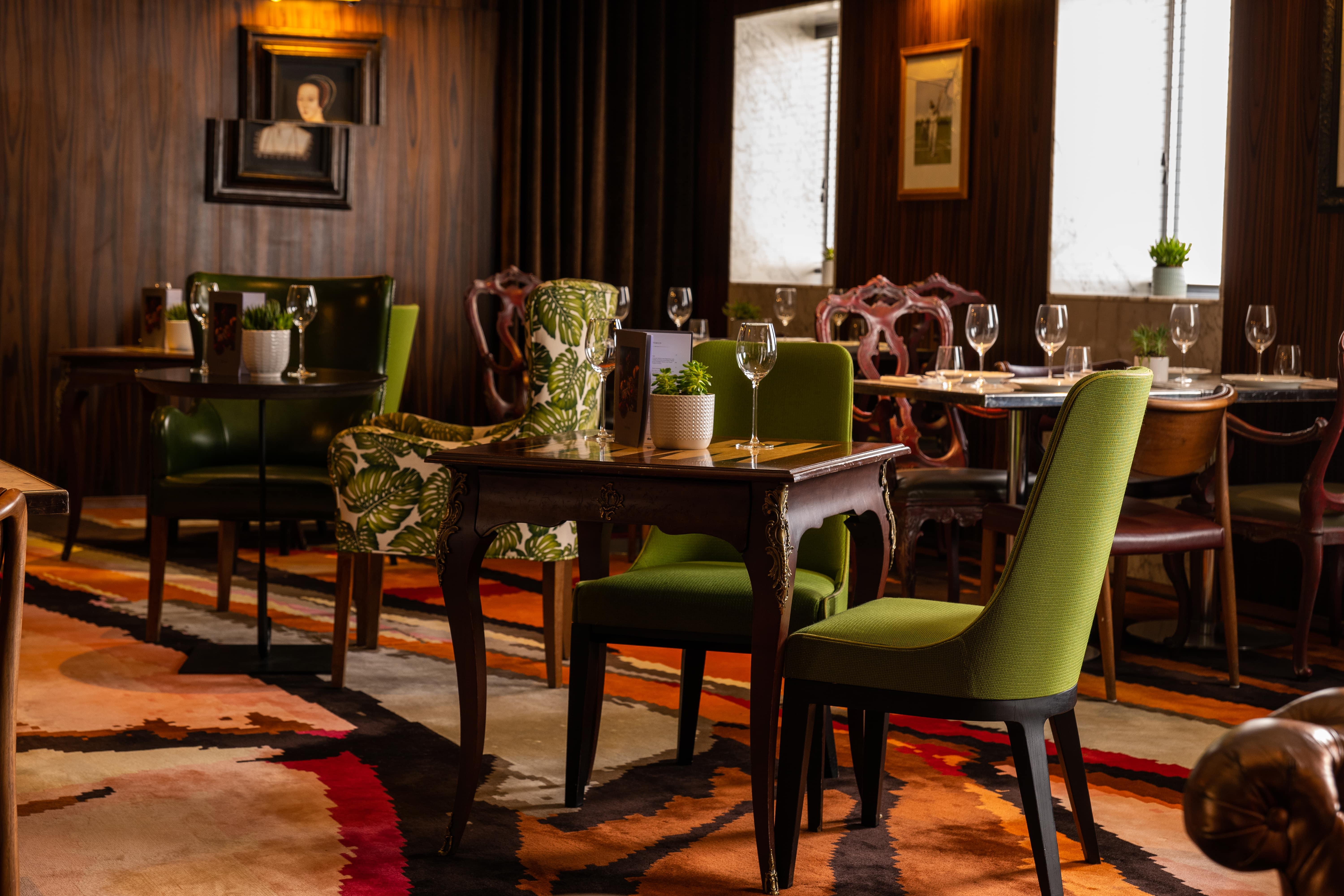 Hotel St Martins Lane Londra Esterno foto The image depicts an elegant dining area with a blend of classic and contemporary design elements. There are several tables arranged neatly, each accompanied by stylish chairs. Some chairs have vibrant green upholstery and unique patterns, while othe