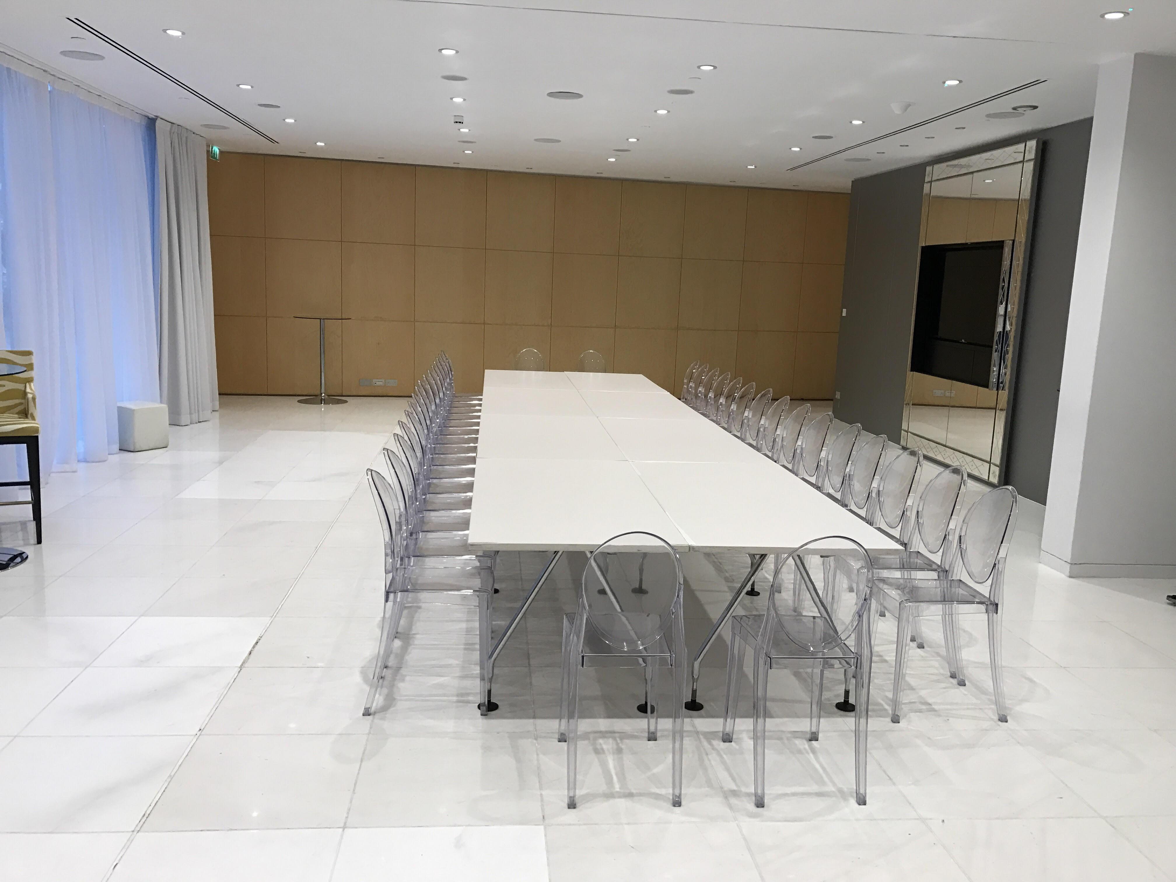 Hotel St Martins Lane Londra Esterno foto The photo shows a modern meeting room or conference space. There is a long rectangular table in the center, surrounded by transparent acrylic chairs. The room features white marble flooring and appears bright due to the overhead lighting. On one side