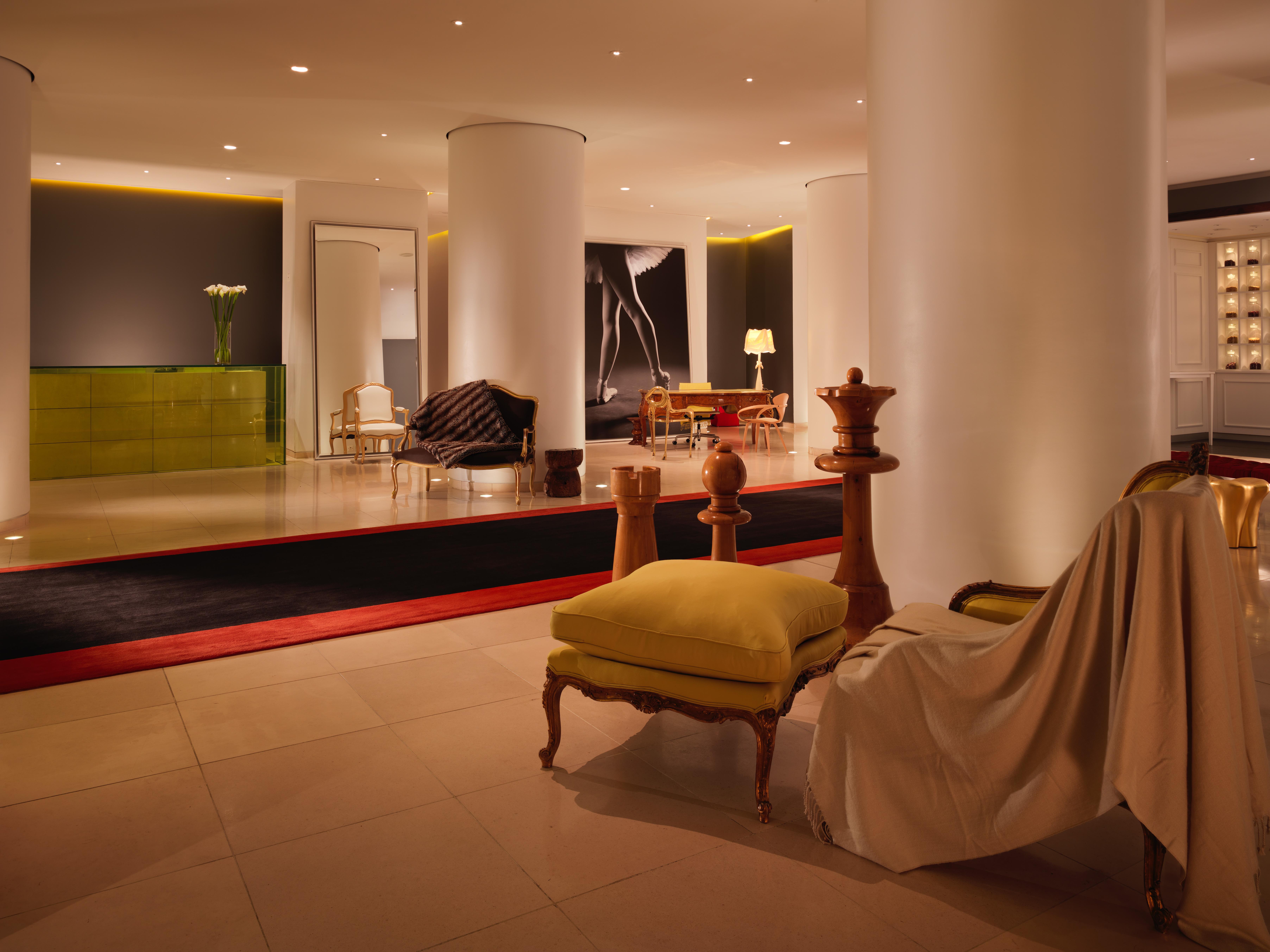 Hotel St Martins Lane Londra Esterno foto The photo shows a modern, stylish hotel lobby. It features a spacious open area with sleek white columns and subtle lighting. There are various seating arrangements, including a sofa and armchairs, with a mix of contemporary and classic design elemen