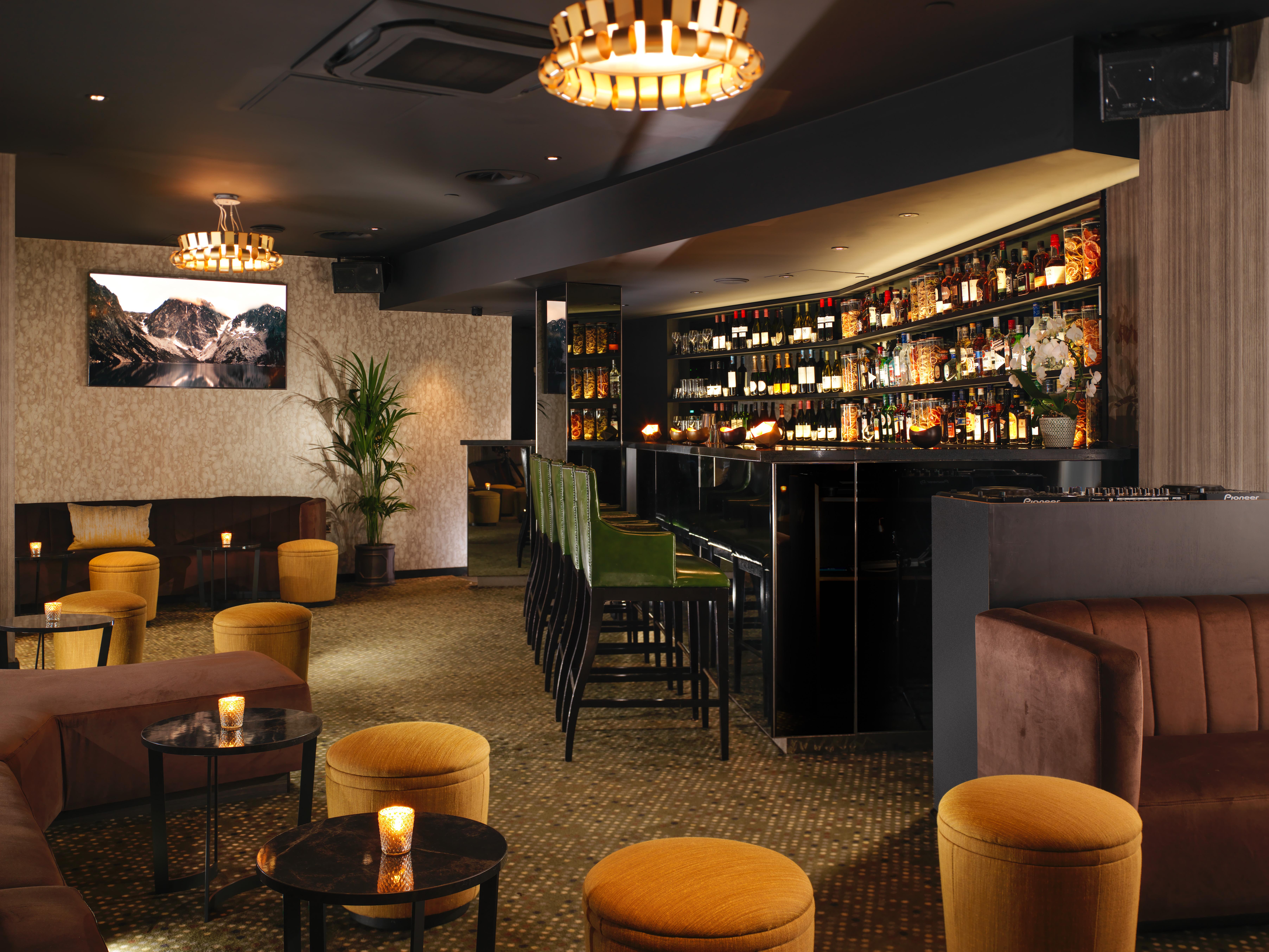 Hotel St Martins Lane Londra Esterno foto The photo depicts a stylish bar or lounge interior. The space features a dark, sophisticated color scheme with plush seating, including brown couches and vibrant yellow stools. A illuminated bar area is prominently displayed, lined with various bottl
