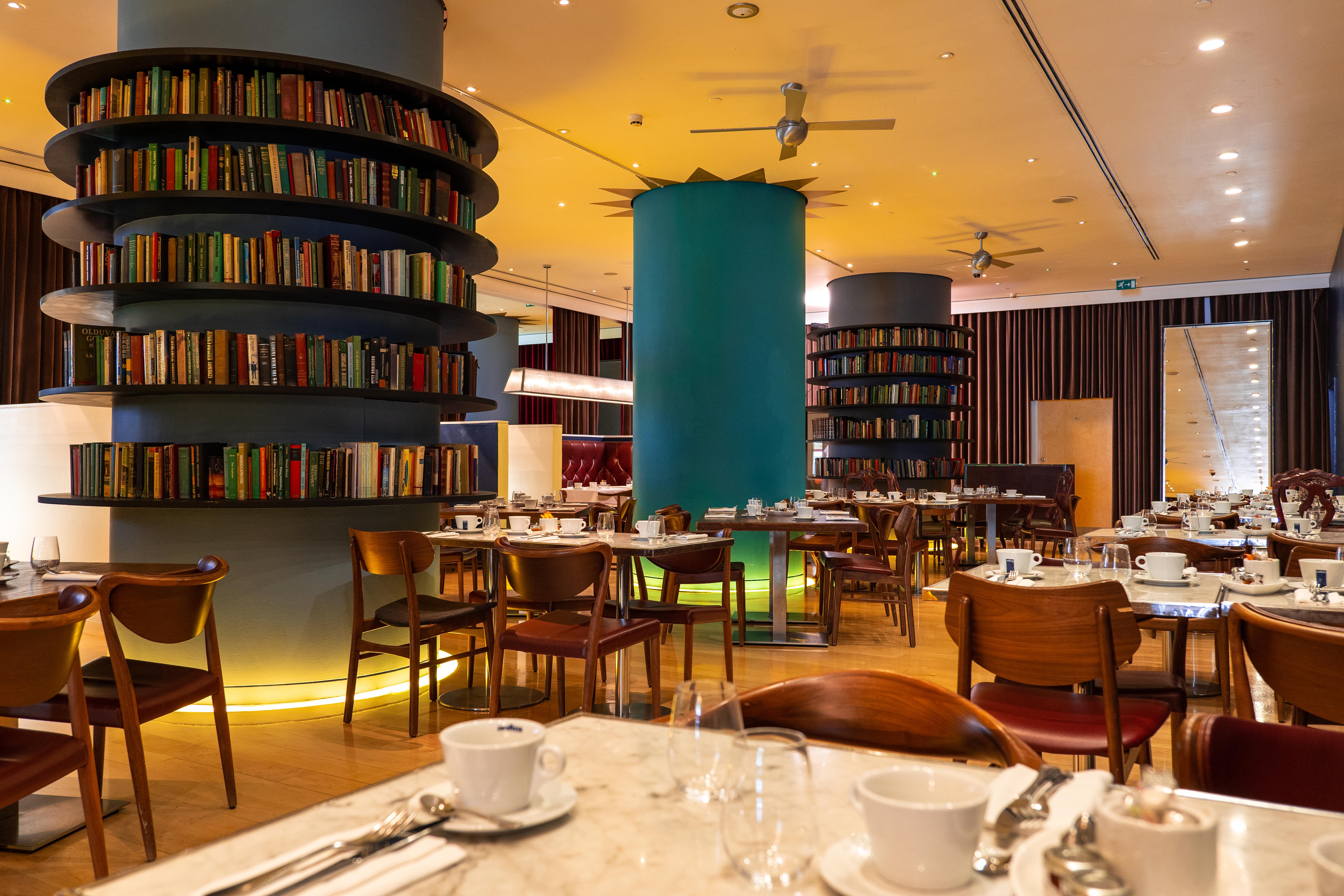 Hotel St Martins Lane Londra Esterno foto The photo depicts a modern restaurant interior featuring a warm and inviting design. There are round tables set for dining, each equipped with white tableware and cutlery. The restaurant has wooden chairs and is illuminated with soft lighting. 

Nota