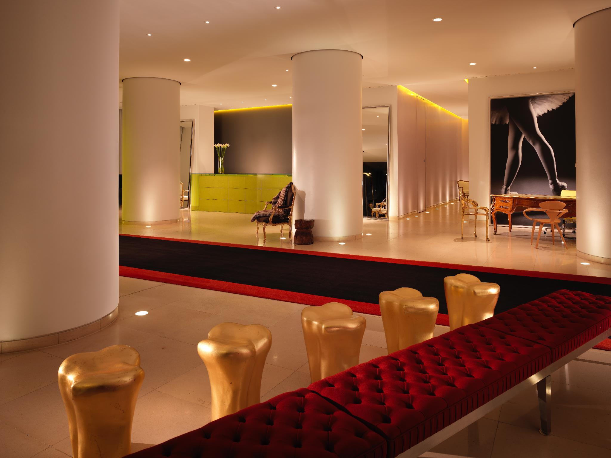 Hotel St Martins Lane Londra Esterno foto The photo shows a modern and stylish interior space, possibly a lobby or a lounge area. It features sleek white pillars and a polished floor, illuminated by soft ambient lighting. On one side, there is a green seating area, while on the opposite side