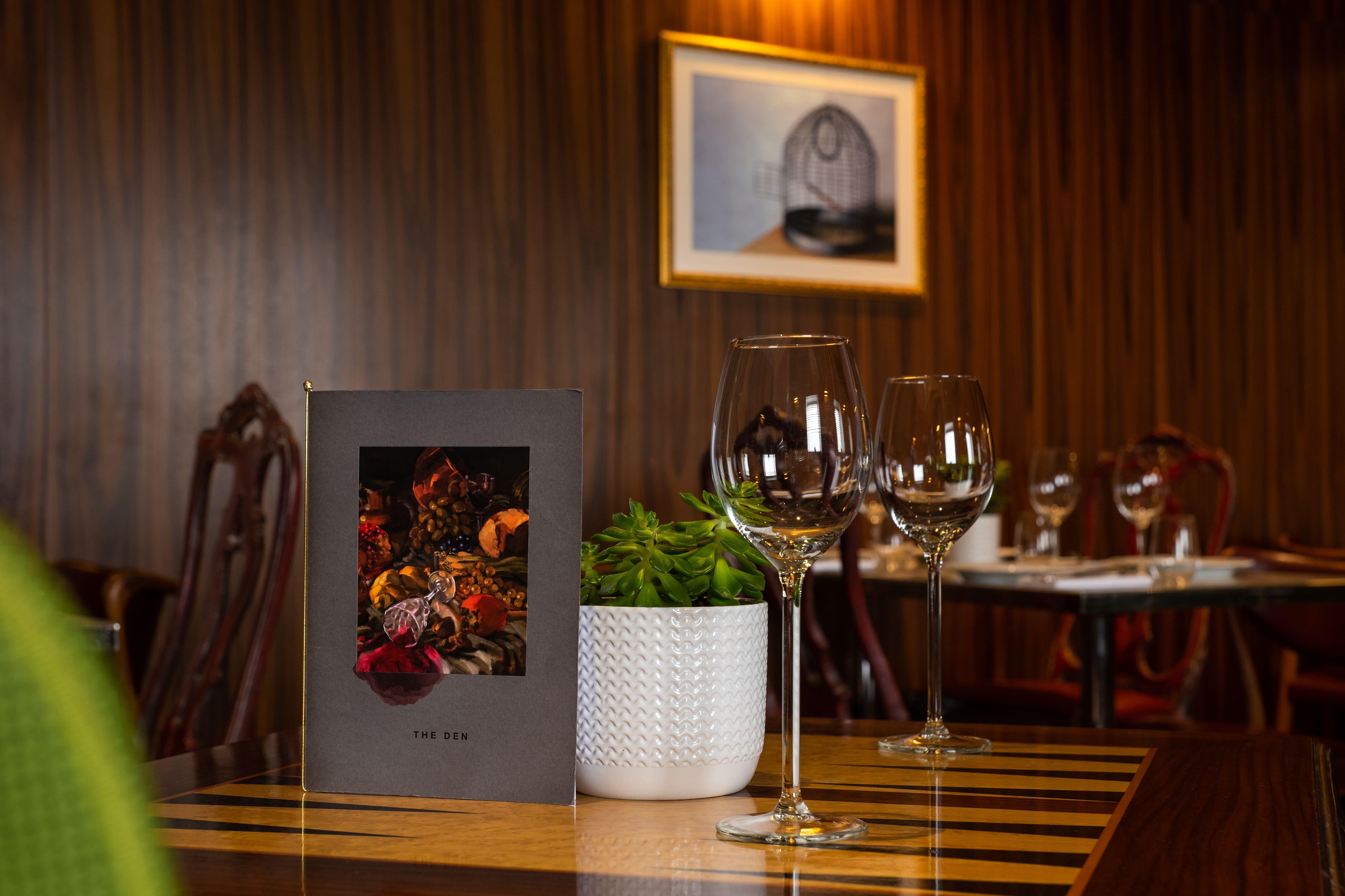 Hotel St Martins Lane Londra Esterno foto The photo shows a cozy dining setting in a restaurant. A menu is prominently displayed on the table, featuring a colorful design that includes images of spices or garnishes. Next to the menu, there are two elegant wine glasses, reflecting the ambianc