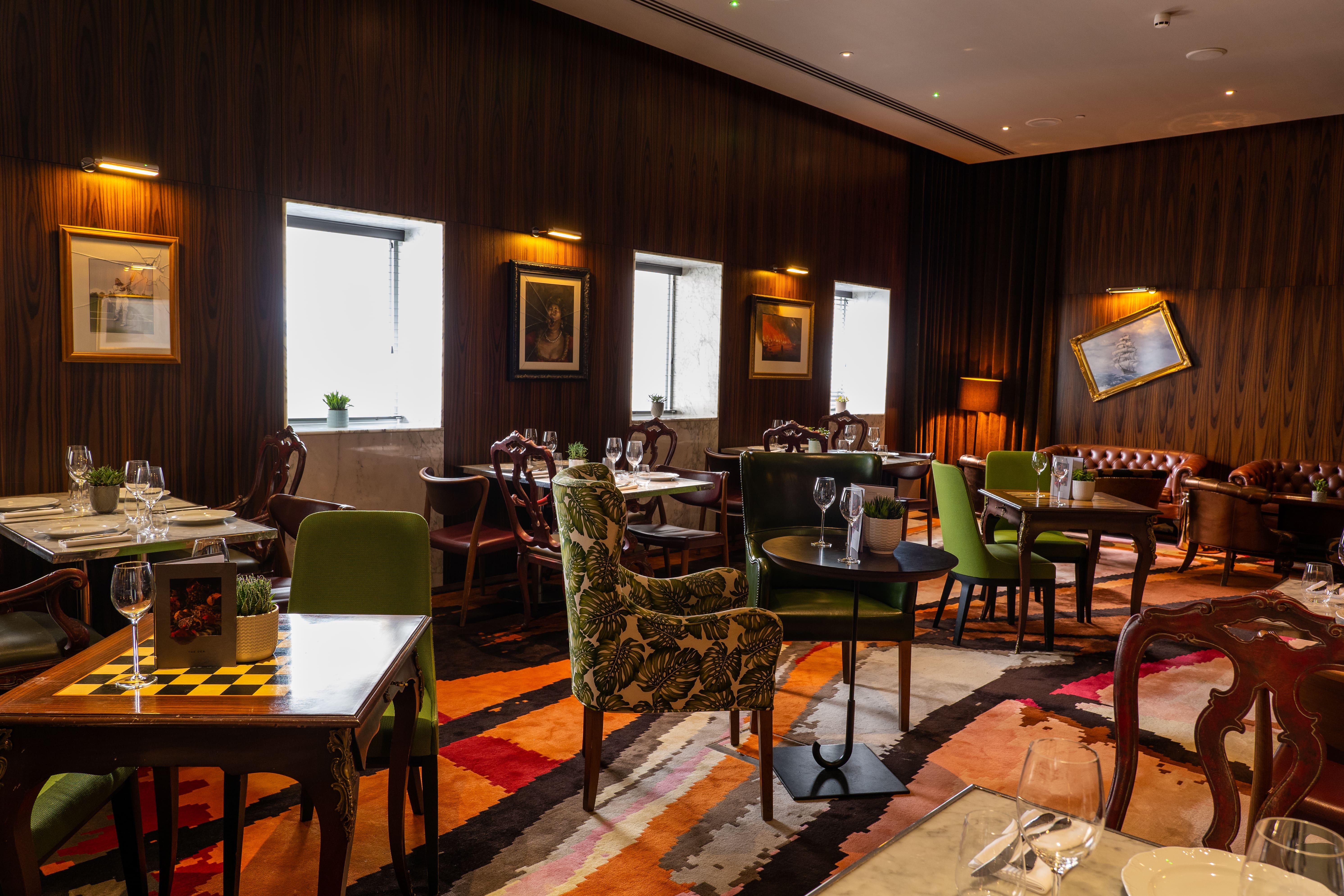 Hotel St Martins Lane Londra Esterno foto The photo depicts an elegantly designed restaurant interior. It features a combination of wooden walls and warm lighting, creating a cozy atmosphere. The seating comprises various styles of chairs, some with colorful upholstery and patterns. Tables a