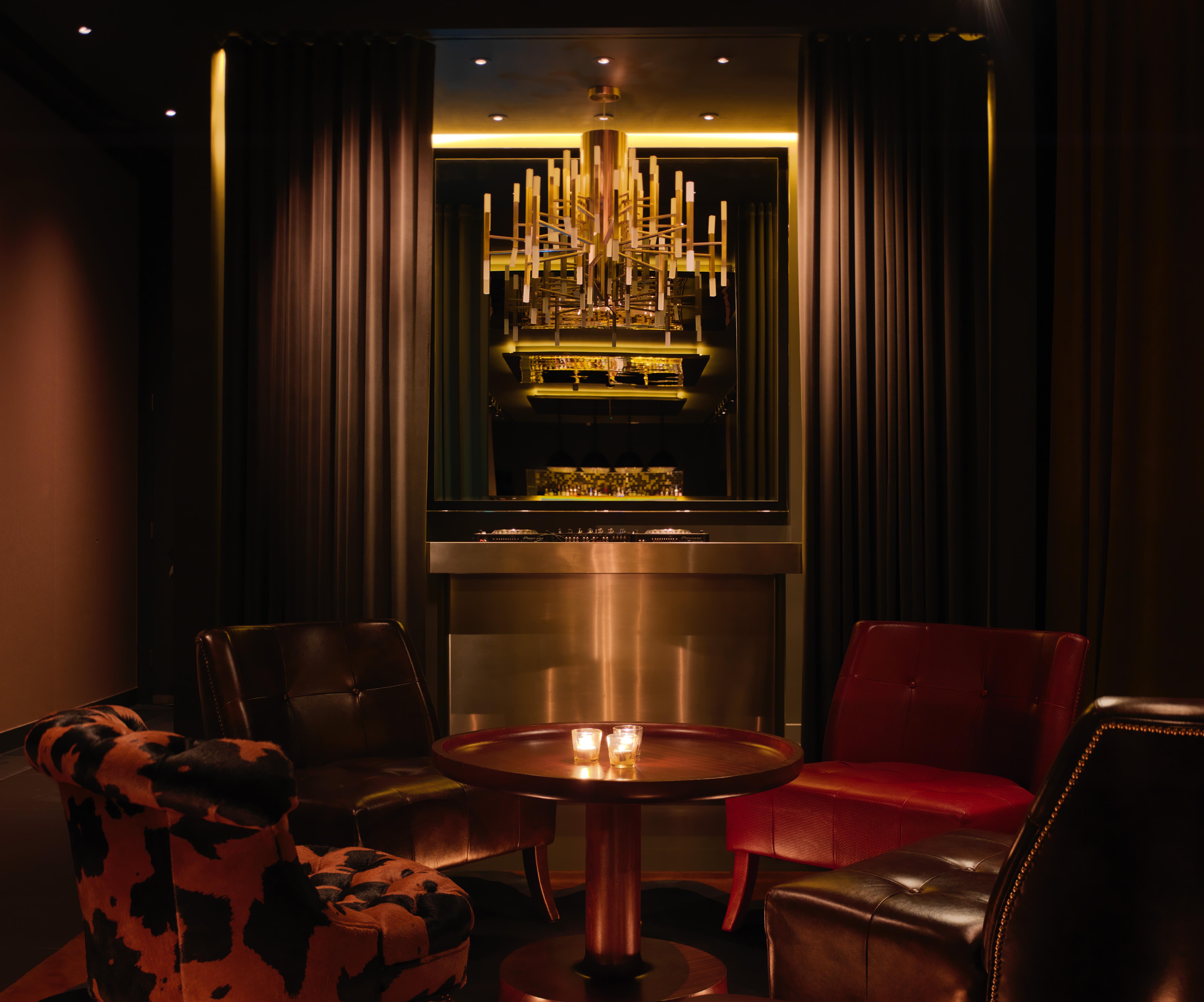 Hotel St Martins Lane Londra Esterno foto The photo depicts a stylish and elegant lounge area. There are two armchairs, one in a deep red and another upholstered in a cowhide pattern. A round table is situated in the center, with two lit candles adding a warm ambiance. In the background, the