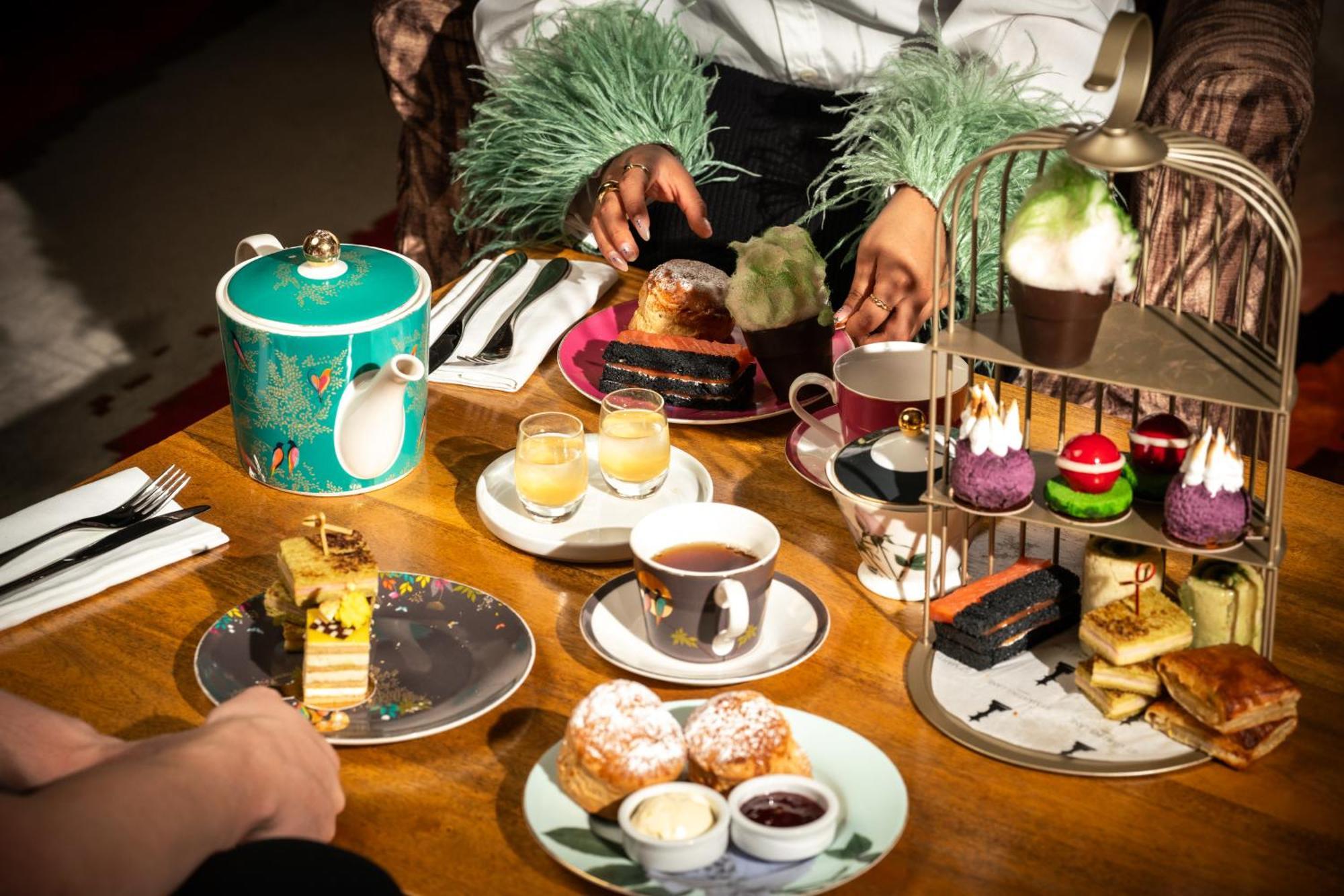 Hotel St Martins Lane Londra Esterno foto The photo features a beautifully arranged afternoon tea setting. In the center, there's an elegant tiered stand filled with various desserts, including colorful cupcakes and small pastries. Surrounding the stand are plates with additional treats, suc