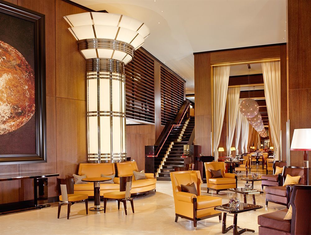 Hotel St Martins Lane Londra Esterno foto The photo depicts a sophisticated and elegant hotel lobby. The interior features a modern design with polished wooden accents and warm lighting. In the center, there is a large, stylish column with art deco elements. Surrounding the column are plush 