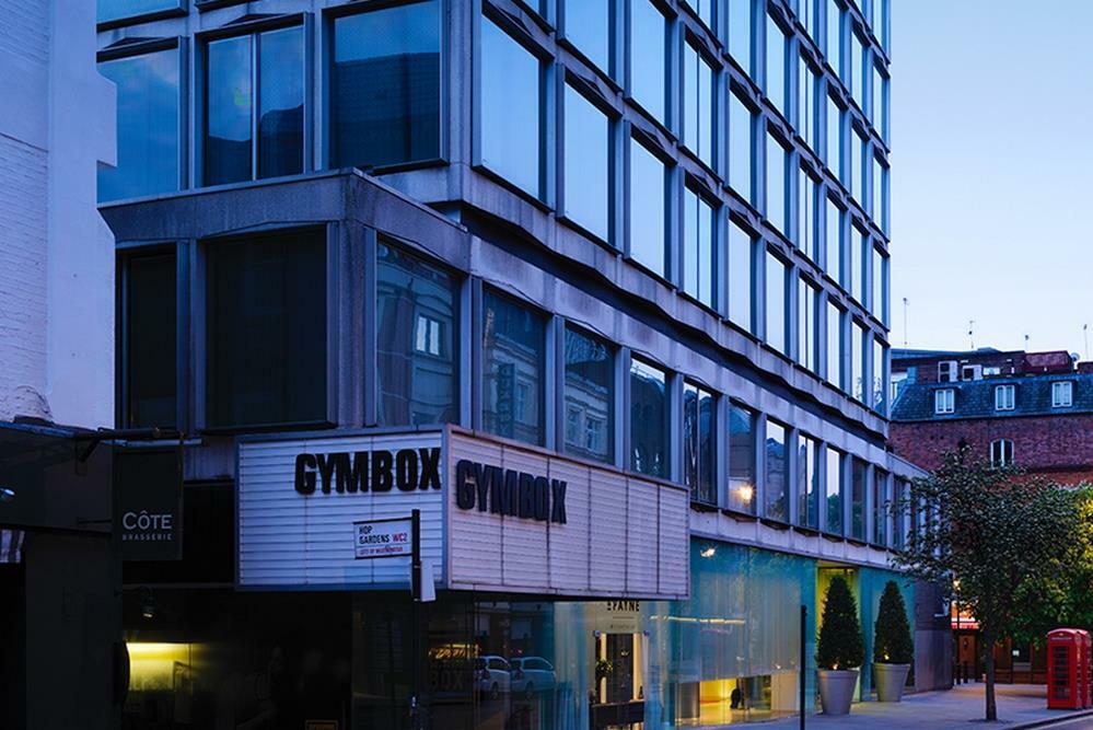 Hotel St Martins Lane Londra Esterno foto The image shows a modern building with a distinctive architectural design. The facade features large glass windows, and the lower section includes a sign that reads "GYMBOX." There appears to be some greenery in front of the building, and the scene i
