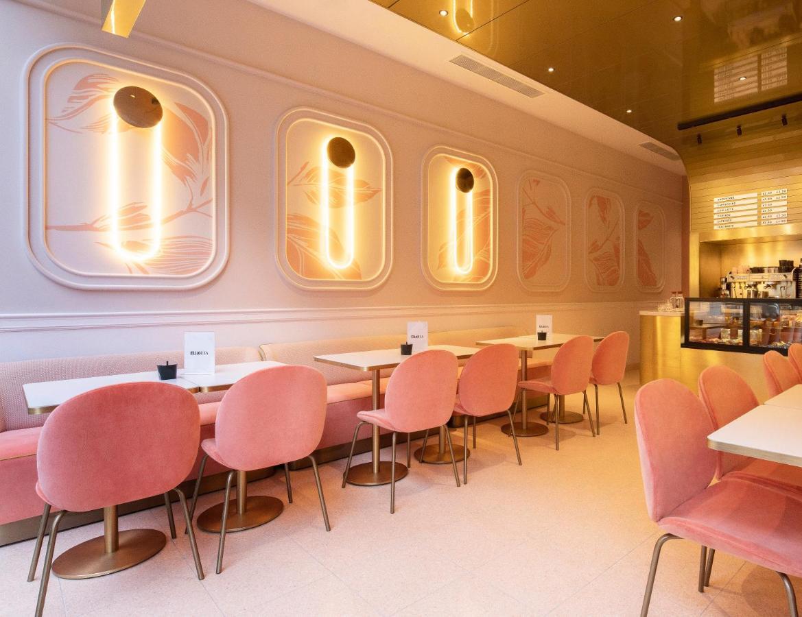 Hotel St Martins Lane Londra Esterno foto The photo depicts a stylish cafe or restaurant interior. The walls are adorned with soft pastel colors, particularly muted pink tones, and feature elegant, abstract designs. There are modern pendant lights mounted on the walls, which provide warm lig